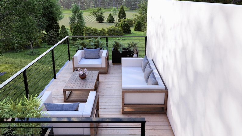K&ouml;nnte beinhalten: Moderne Gartenm&ouml;bel mit Holzrahmen und wei&szlig;en Kissen. Das Set besteht aus zwei Sesseln, einem Sofa und einem Couchtisch. Die Terrasse hat ein Holzdeck und ein schwarzes Gel&auml;nder mit Blick auf einen gr&uuml;nen Rasen und B&auml;ume.