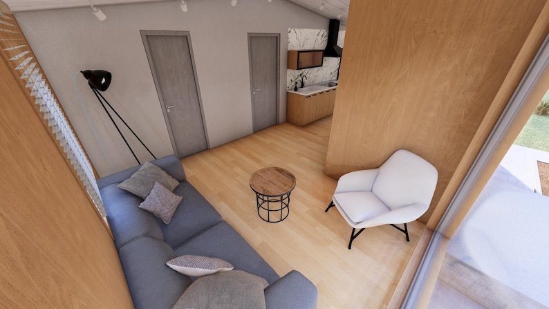 May include: Interior view of a modern living space with a blue sofa, a small round wooden table, and a white armchair. The room has light wood flooring and walls, with two closed doors and a kitchen area visible in the background. A black lamp is mounted on the wall.