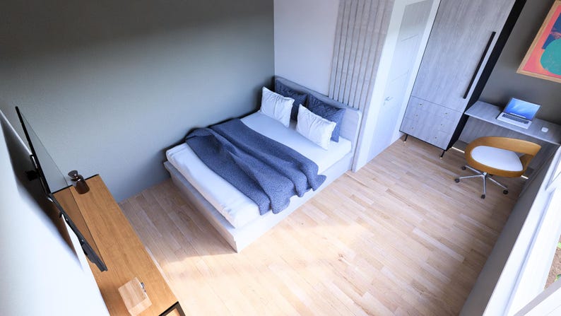 May include: A modern bedroom with a bed, desk, and wardrobe. The bed has white bedding and a blue blanket. A desk with a laptop and a chair are in the corner. The room has light wood flooring and a gray wall.