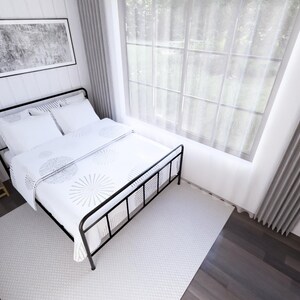 K&ouml;nnte beinhalten: Ein Schlafzimmer mit einem schwarzen Metallbettrahmen, wei&szlig;er Bettw&auml;sche und einer gemusterten Bettdecke. Unter dem Bett liegt ein grauer Teppich. Das Zimmer verf&uuml;gt &uuml;ber ein gro&szlig;es Fenster mit transparenten Vorh&auml;ngen, einen Nachttisch aus Holz und ein gerahmtes Kunstwerk an der Wand.