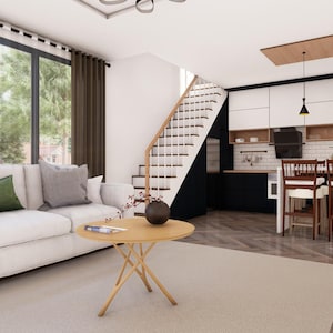 Puede incluir: Interior de un espacio de vida moderno con un sof&aacute; blanco, cojines grises y verdes, y una mesa de centro redonda de madera. La cocina cuenta con gabinetes blancos y negros, una mesa de comedor y una escalera. Grandes ventanales ofrecen vistas a los &aacute;rboles.