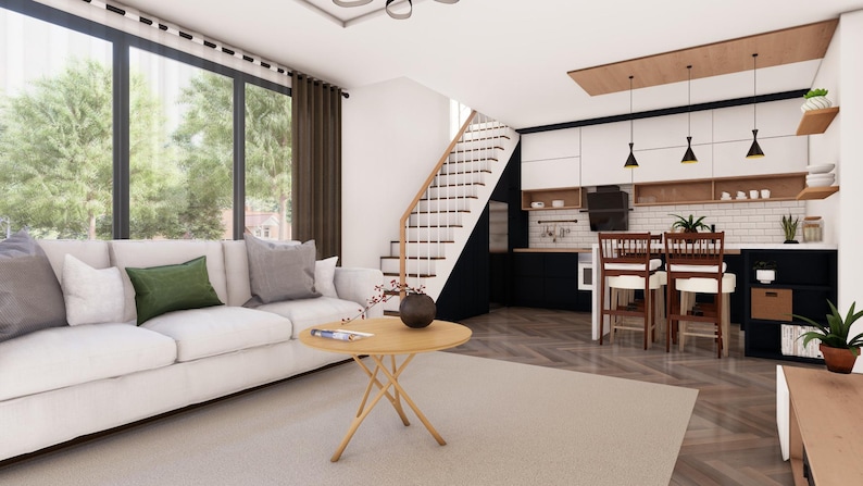 Puede incluir: Interior de un espacio de vida moderno con un sof&aacute; blanco, cojines grises y verdes, y una mesa de centro redonda de madera. La cocina cuenta con gabinetes blancos y negros, una mesa de comedor y una escalera. Grandes ventanales ofrecen vistas a los &aacute;rboles.