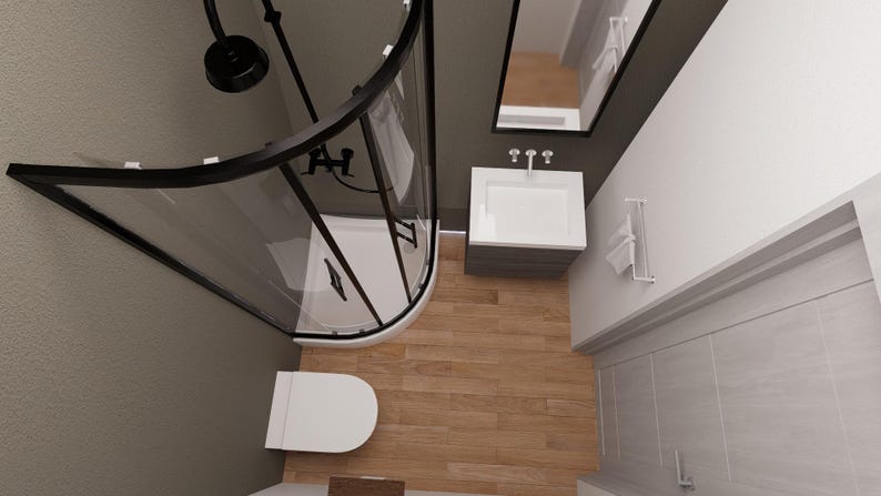 May include: An overhead view of a modern bathroom with a black-framed shower enclosure, a white toilet, and a vanity with a mirror. The floor is wood-toned, and the walls are painted in neutral colors. The shower head is black.
