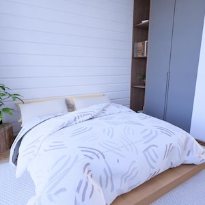 Puede incluir: Un dormitorio con una cama, una planta y un armario. La cama tiene un edred&oacute;n y almohadas con estampado blanco y gris. Una planta verde se encuentra sobre un toc&oacute;n de madera. Un armario gris est&aacute; a la derecha.