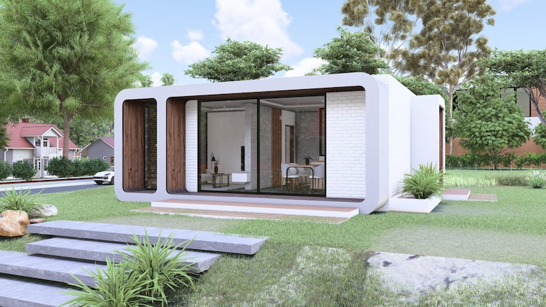 Peut inclure: Maison modulaire blanche et moderne avec de grandes fen&ecirc;tres en verre et des accents en bois. La maison est entour&eacute;e d'herbe verte, d'arbres et d'un chemin en pierre. Le design est contemporain et minimaliste.