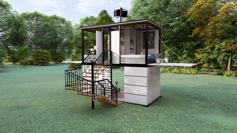 Op de afbeelding: Een modern, tweelaags tiny house met een zwart frame en witte buitenkant. Het huis heeft een wenteltrap, een klein balkon en een dakconstructie. Het staat op een groen gazon met bomen op de achtergrond.