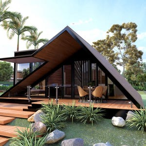 May include: A-frame house with a black frame and wooden accents. The house has large glass windows and doors, a wooden deck, and a barbecue grill. Palm trees and lush greenery surround the house. The house is on a grassy hill with large rocks.