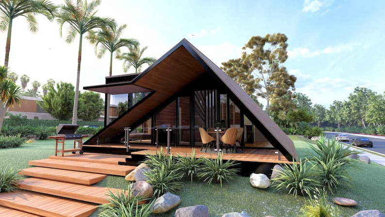 May include: A-frame house with a black frame and wooden accents. The house has large glass windows and doors, a wooden deck, and a barbecue grill. Palm trees and lush greenery surround the house. The house is on a grassy hill with large rocks.