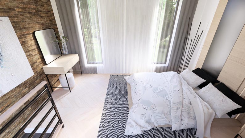 May include: A modern bedroom interior with a white bed, pillows, and a patterned blanket. A black and white patterned rug is on the floor. A white desk with a black frame and a mirror are against a brick wall.