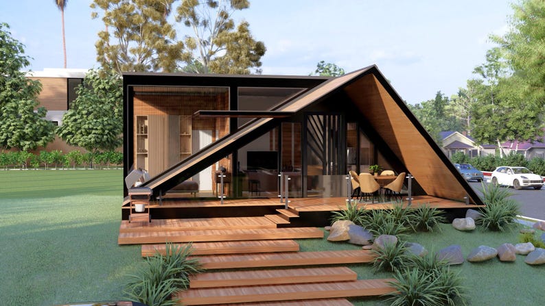 May include: A modern, architectural rendering of a small house with a unique A-frame roof design. The house features a wooden deck, glass walls, and a minimalist interior. Landscaping includes grass, plants, and stone accents.