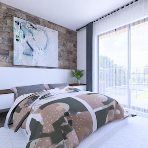 May include: A modern bedroom with a large bed featuring a patterned comforter in shades of brown, green, and white. The room has a stone accent wall, a large window with gray curtains, and a piece of abstract art above the bed.