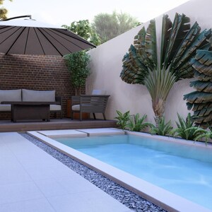 May include: A rectangular swimming pool with light blue water sits beside a wooden deck featuring a beige sofa, a dark coffee table, and a large cantilevered umbrella. A brick wall and large fan-shaped green plants line the patio area.