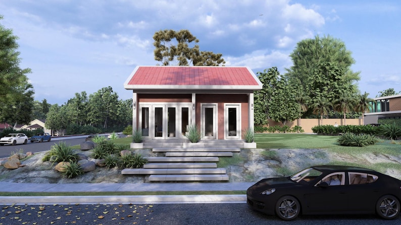 May include: A small, modern building with a red roof and white trim. The building has multiple glass doors and windows. A black car is parked in front of the building on a paved road. Landscaping includes bushes, rocks, and trees.