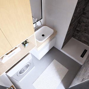 Op de afbeelding: Een moderne badkamer met een licht houten kast, een witte wastafel en een wasmachine. De doucheruimte heeft donkere, steenachtige tegels. Een wit tapijt ligt op de vloer.