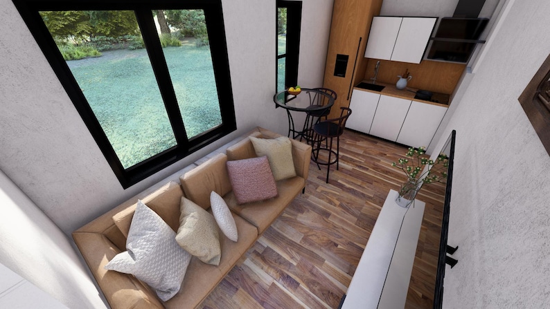 May include: Interior view of a modern living space with a tan sofa and decorative pillows. A small round table with two chairs is near a window overlooking a green lawn. The kitchen has white cabinets and a black countertop.