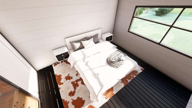 May include: A modern bedroom interior featuring a white bed with pillows and a blanket. Two white nightstands with black drawers flank the bed. A cowhide rug in shades of brown and white sits on the dark wood floor. A large window offers a view of the outdoors.
