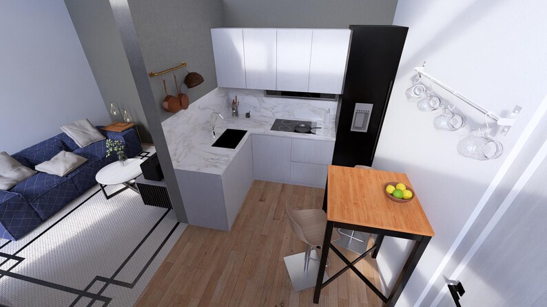 May include: An overhead view of a modern, compact kitchen and living space. The kitchen features white cabinets, a marble countertop, and a black stovetop. A small wooden table with a bowl of lemons sits nearby. A blue sofa and white rug complete the living area.