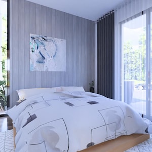 May include: A modern bedroom with a large bed covered in a white duvet with a geometric pattern. The room features large windows with sheer curtains, a piece of abstract art, and a green plant. The walls are a light gray color.