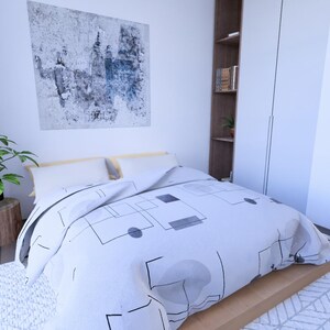Peut inclure: Int&eacute;rieur de chambre avec un lit recouvert d'une couette blanche &agrave; motifs g&eacute;om&eacute;triques. Une plante en pot repose sur une souche de bois et une peinture abstraite est accroch&eacute;e au mur. Une armoire encastr&eacute;e et une porte sont &eacute;galement visibles.