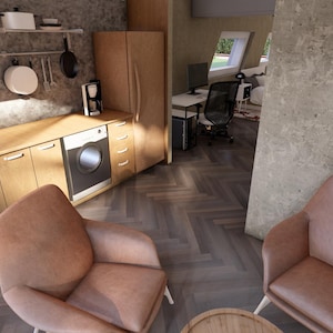 May include: Interior shot of a modern kitchen and living space. The kitchen features wooden cabinets, a black sink, and a washing machine. Two pink armchairs face each other in the living area. The floor has a herringbone pattern.