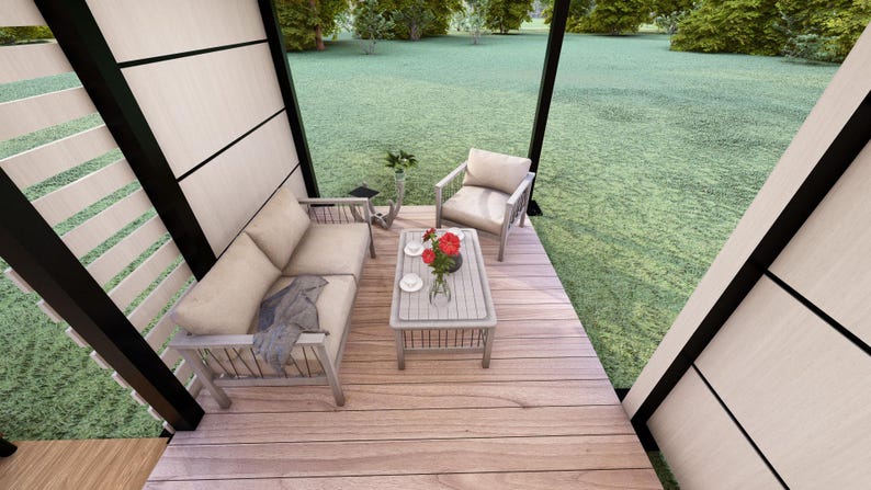 Op de afbeelding: Een buitenruimte met een licht houten bank, fauteuil en salontafel. De salontafel heeft een vaas met rode bloemen en twee kopjes. De ruimte is omgeven door een houten terras en een grasveld.