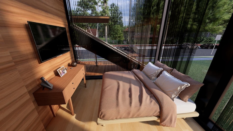 May include: A modern bedroom with a large window overlooking a green landscape. The room features a bed with a brown comforter and white pillows, a wooden dresser, and a mounted television. The walls are paneled with light-colored wood.