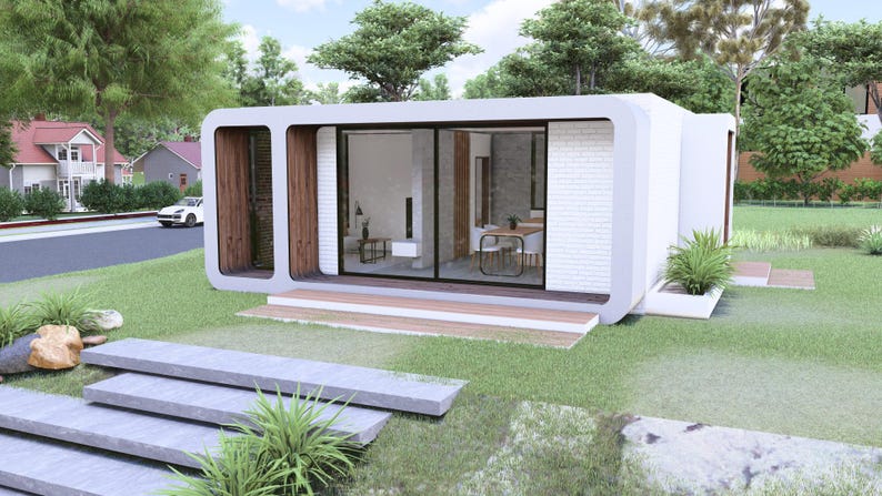Peut inclure: Une maison modulaire blanche moderne avec de grandes portes et fen&ecirc;tres vitr&eacute;es, situ&eacute;e sur une pelouse verte. La maison pr&eacute;sente un design minimaliste avec des accents en bois et un petit porche. L'am&eacute;nagement paysager comprend des marches en pierre et des plantes d&eacute;coratives.