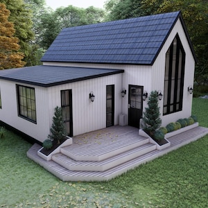 K&ouml;nnte beinhalten: Ein wei&szlig;es Haus mit einem dunkelblauen Schindeldach und schwarzen Zierleisten. Das Haus hat eine kleine Veranda mit Stufen, eine schwarze T&uuml;r und mehrere Fenster. Das Haus ist von gr&uuml;nem Gras und B&auml;umen umgeben.