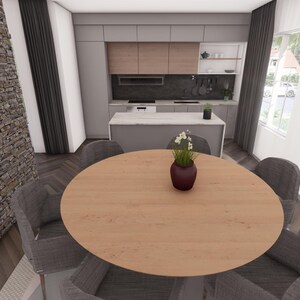 May include: Interior shot of a modern kitchen and dining area. A round wooden dining table is surrounded by four gray upholstered chairs. A small vase with flowers sits on the table. The kitchen features light wood cabinets and a gray island.
