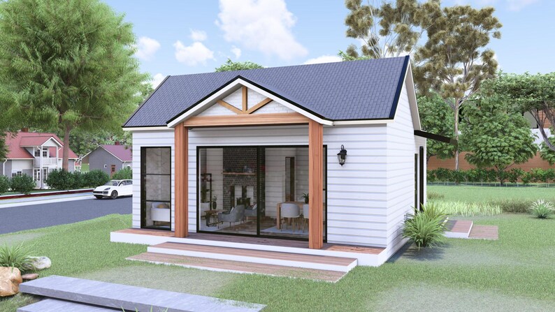 Puede incluir: Una casa peque&ntilde;a y moderna con exterior blanco, tejado gris oscuro y porche de madera. La casa tiene grandes puertas correderas y ventanas de cristal, rodeada de c&eacute;sped verde y &aacute;rboles. Un coche blanco est&aacute; aparcado en la calle.