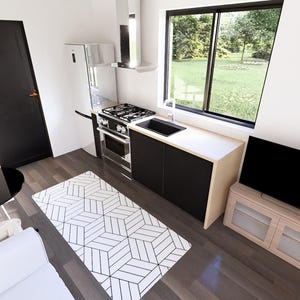 K&ouml;nnte beinhalten: Innenaufnahme einer modernen, minimalistischen K&uuml;che und eines Wohnbereichs. Zu den Merkmalen geh&ouml;ren eine schwarze T&uuml;r, ein K&uuml;hlschrank aus Edelstahl, ein Herd und eine schwarze Arbeitsplatte. Ein geometrisch gemusterter Teppich und ein schwarzer Fernseher sind ebenfalls sichtbar.