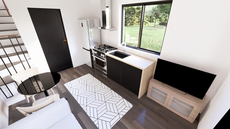 K&ouml;nnte beinhalten: Innenaufnahme einer modernen, minimalistischen K&uuml;che und eines Wohnbereichs. Zu den Merkmalen geh&ouml;ren eine schwarze T&uuml;r, ein K&uuml;hlschrank aus Edelstahl, ein Herd und eine schwarze Arbeitsplatte. Ein geometrisch gemusterter Teppich und ein schwarzer Fernseher sind ebenfalls sichtbar.