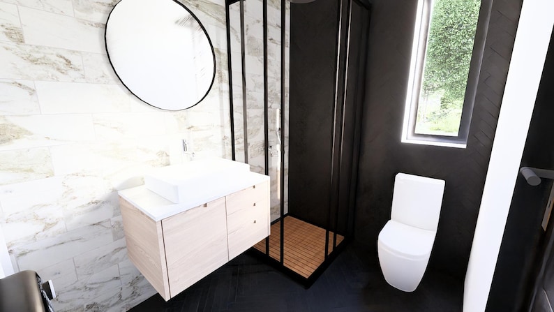 K&ouml;nnte beinhalten: Modernes Badezimmer-Design mit einem wei&szlig;en, rechteckigen Waschbecken auf einem hellen Holzwaschtisch. Ein gro&szlig;er, runder Spiegel mit schwarzem Rahmen h&auml;ngt dar&uuml;ber. Eine schwarz gerahmte Duschkabine und eine wei&szlig;e Toilette vervollst&auml;ndigen den Raum.