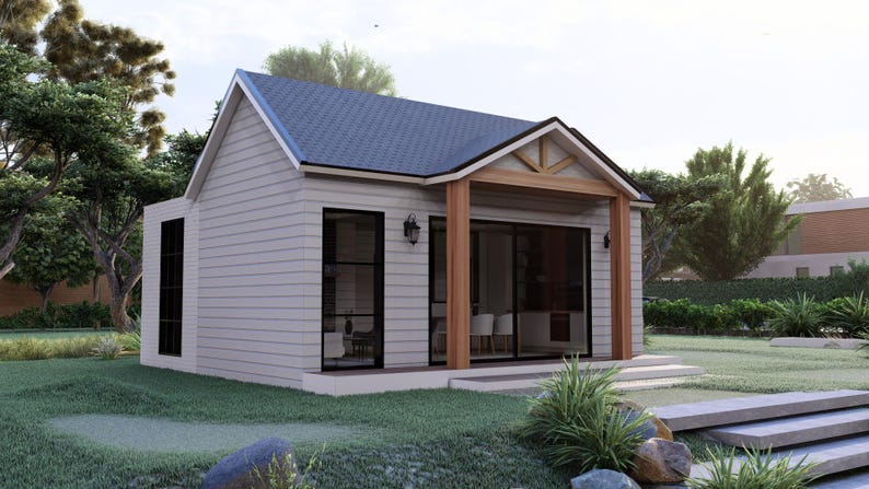 Puede incluir: Una peque&ntilde;a casa gris claro con un tejado azul oscuro y detalles en madera. La casa tiene grandes ventanas y un porche, situada en un jard&iacute;n verde con &aacute;rboles y paisajismo. El dise&ntilde;o es moderno y acogedor.