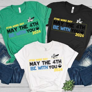 Puede incluir: Tres camisetas en verde, negro y blanco con el texto "STAR WARS DAY MAY THE 4TH BE WITH YOU 2024" y un gráfico de un Stormtrooper.