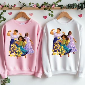 May include: Two pink and white sweatshirts with a graphic print of three women with butterflies. The women are wearing colorful dresses and have brown hair. The butterflies are yellow and gold.