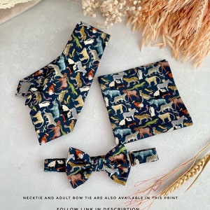 May include: A set of three bow ties featuring a dark blue background with a colorful animal print. The set includes a standard bow tie, a smaller bow tie, and a pocket square.