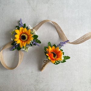 May include: Two sunflower boutonnieres with burlap ribbon and sprigs of lavender. The boutonnieres are tied with twine.