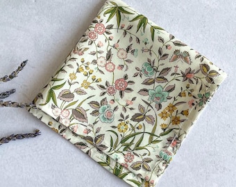 May include: A square fabric pocket square featuring a cream background with a dense botanical print of pink, yellow, and teal flowers, green leaves, and small butterflies. The edges are finished with a clean, straight stitched hem.