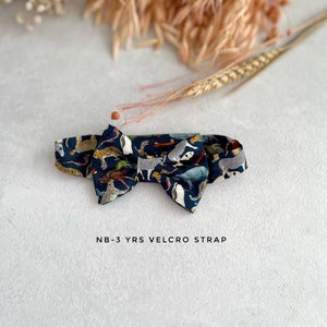 May include: A dark blue bow tie with a colorful animal print pattern. The bow tie has a velcro strap and is labeled "NB-3 YRS VELCRO STRAP".