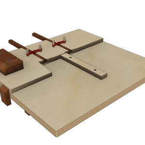 May include: A wooden jig with a brown leather-covered component and red metal clamps. The jig has a rectangular base with a cutout and several wooden and metal components attached. The design appears to be for woodworking or a similar craft.