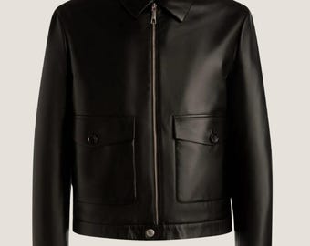 May include: A black leather jacket with a zip fastening and two large pockets. The jacket has a collar and long sleeves.
