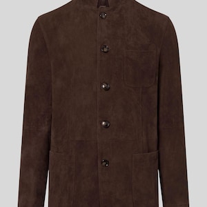 Puede incluir: Chaqueta de ante marrón con cuello mandarín, cuatro botones y dos bolsillos delanteros. La chaqueta tiene un corte entallado y un diseño clásico. La chaqueta está hecha de un material suave y texturizado.