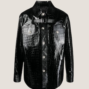 May include: A black leather shirt with a crocodile pattern. The shirt has a button-up front, long sleeves, and a belt at the waist.