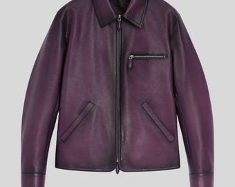 May include: A purple leather jacket with a collar, a front zipper, and a chest pocket. The jacket has a classic design with a slightly faded appearance. The cuffs and collar are dark purple.