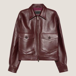 May include: A burgundy leather jacket with a collared neckline and a front zip. It has two front pockets with button fastenings. The interior lining is a contrasting colour. A classic outerwear garment.