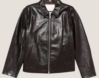 May include: A dark brown leather jacket with a zip fastening and two pockets.