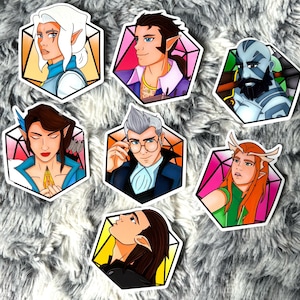 May include: A collection of seven fantasy character stickers. Each sticker features a different character portrait within a hexagonal frame. The characters have various skin tones, hair colors, and attire, with some wearing elven ears or horns.