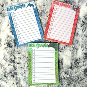 Könnte beinhalten: Drei farbige Notizblöcke mit dem Text "Side Quests" und einer Gamecontroller-Grafik. Die Blöcke sind blau, rot und grün, jeweils mit einem anderen Bordürendesign und einer Checkliste für Aufgaben.