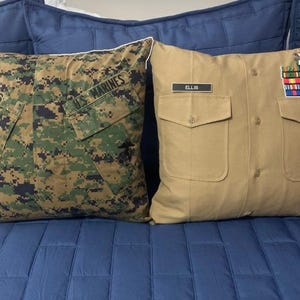 May include: Two decorative pillows, one with a camouflage pattern and the text "US Marines" and the other with a tan fabric and the text "ELLIS".